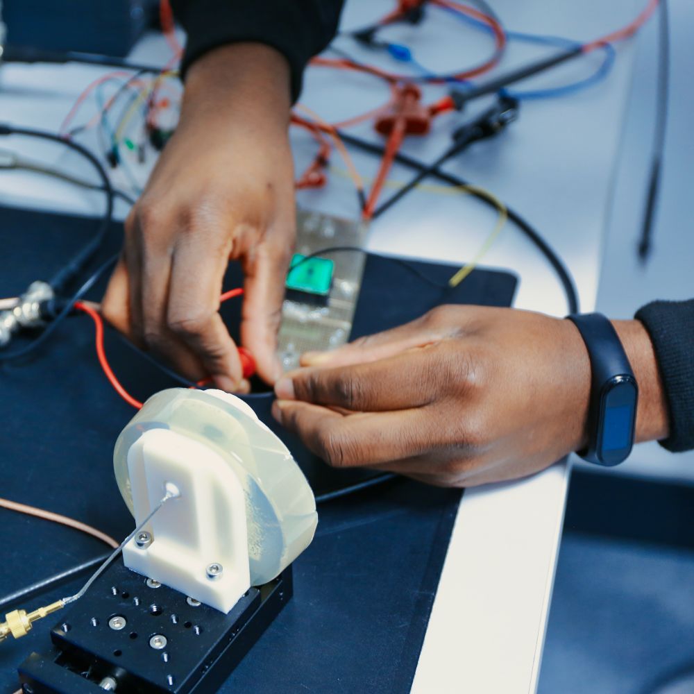 two hands doing a test bench of a transcutaneous wireless ultrasound power transmission